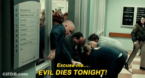 Group In Hallway With Sign Saying Evil Dies Tonight GIF
