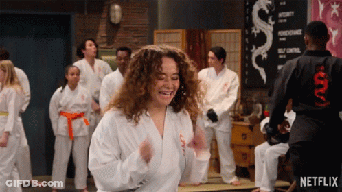 Group In Karate Uniforms Dancing In Front Of Netflix Sign GIF