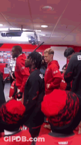 Group In Red And Black Shirts Standing In Room GIF