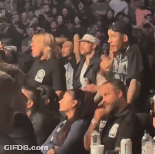 Group In Stadium With Man In Black Shirt Saying MK GIF