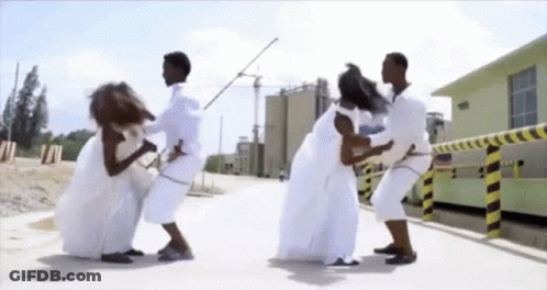 Group In White Clothes Standing On Sidewalk GIF