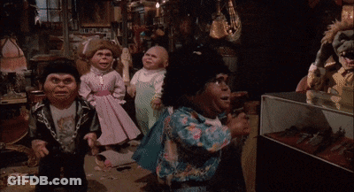Group Of Dolls Standing In Room With Display Case GIF