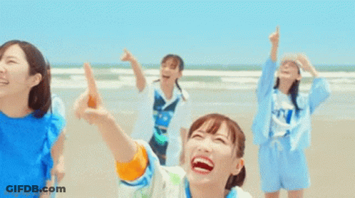 Group Of Girls Laughing And Pointing At Sky On Beach GIF