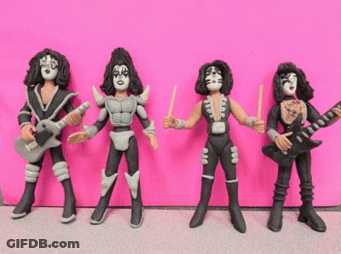 Group Of Kiss Figurines Lined Up Against Pink GIF