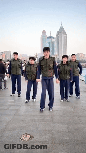 Group Of Men On Sidewalk In Front Of City GIF