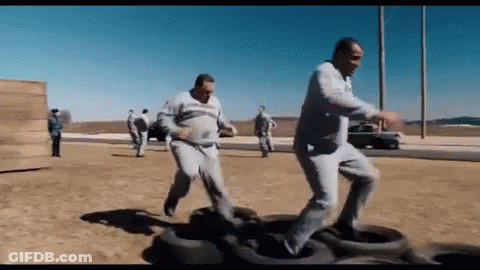 Group Of Men Playing With Tires In Desert GIF