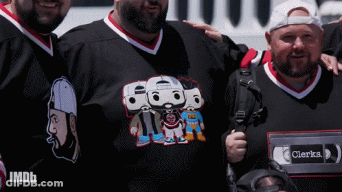 Group Of Men Posing One Wearing Clerks Shirt GIF