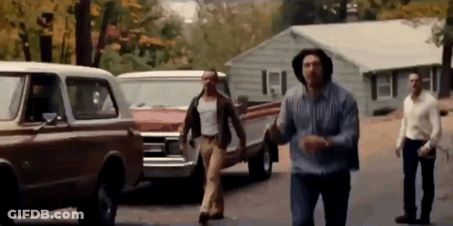 Group Of Men Walking On Street Near House GIF