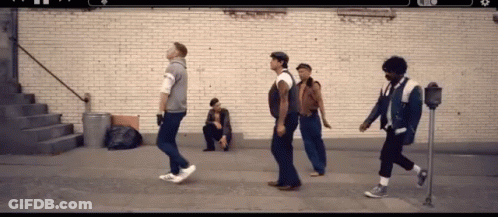 Group Of Men Walking Past Man Sitting On Sidewalk GIF