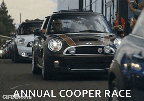 Group Of Mini Cooper Cars Driving Down Street With Words Annual Cooper Race GIF