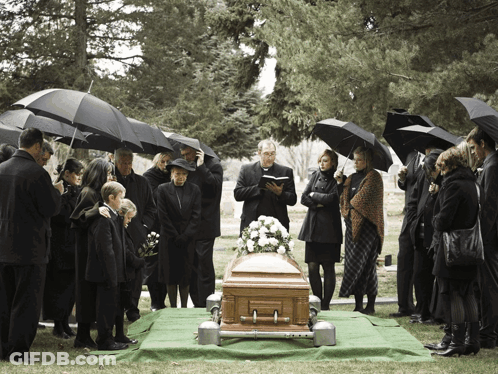 Group Of People Around Coffin In Cemetery Under Umbrellas GIF