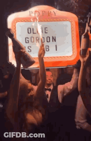 Group Of People Dancing In Front Of Poppy Sign GIF