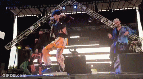 Group Of People Dancing On Stage In Front Of Large Light GIF