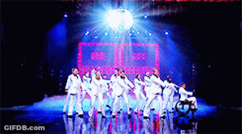 Group Of People Dancing On Stage With Disco Ball GIF
