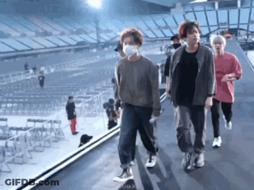 Group Of People In Face Masks Walking On Stage In Stadium GIF