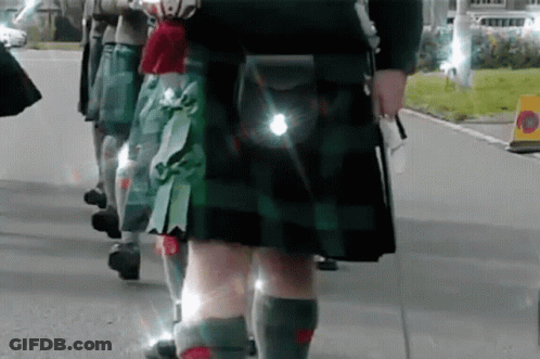 Group Of People In Kilts Walking Down Street GIF