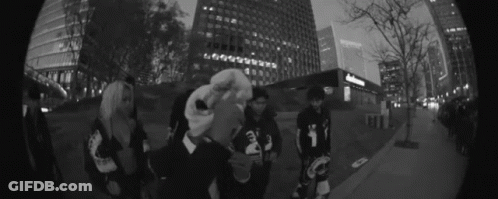 Group Of People On Sidewalk In Front Of Tall Buildings GIF
