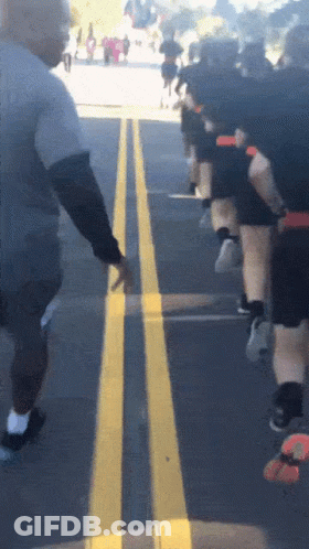 Group Of People Running Down Street With Yellow Line GIF