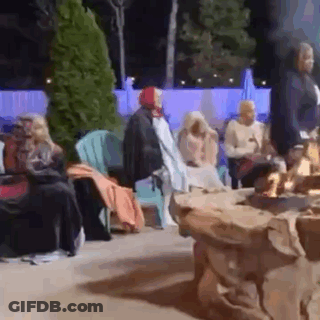 Group Of People Sitting Around Fire Pit At Night GIF