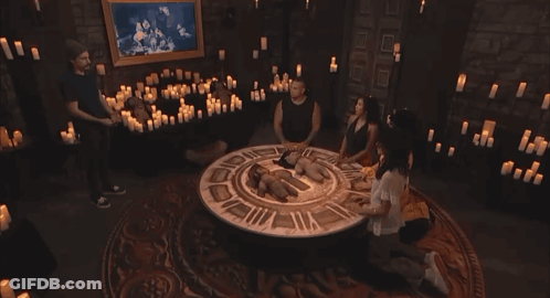 Group Of People Sitting Around Table With Candles And Clock GIF
