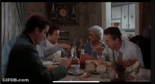 Group Of People Sitting Around Table With Clock GIF
