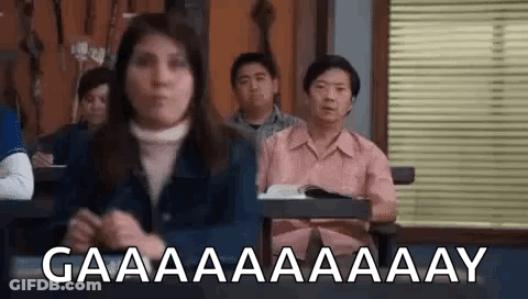 Group Of People Sitting At Desks In Classroom With Woman Standing In Front GIF