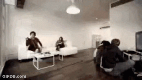 Group Of People Sitting In Living Room With Couch And Table GIF