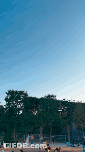 Group Of People Sitting In Park With Blue Sky GIF