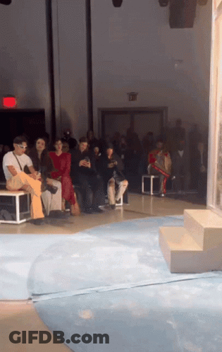 Group Of People Sitting In Room With Red Exit Sign GIF