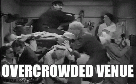 Group Of People Standing Around Table Overcrowded Venue GIF