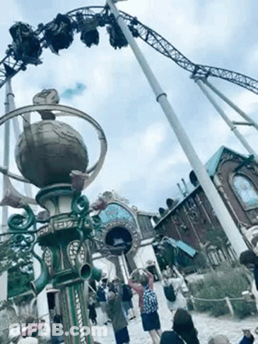 Group Of People Standing In Front Of A Roller Coaster GIF