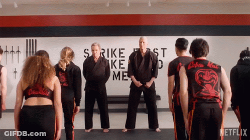 Group Of People Standing In Front Of Strike First Strike Me Wall GIF