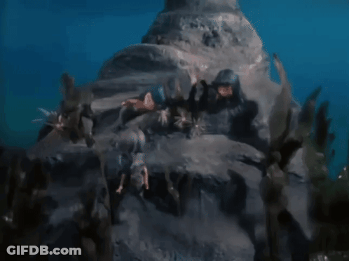 Group Of People Swimming In Ocean Near Rock GIF
