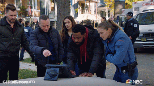 Group Of Police Officers Looking At Tablet On Car Hood GIF