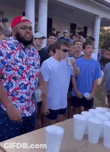 Group Of Young Men Standing Around Table With Cups GIF