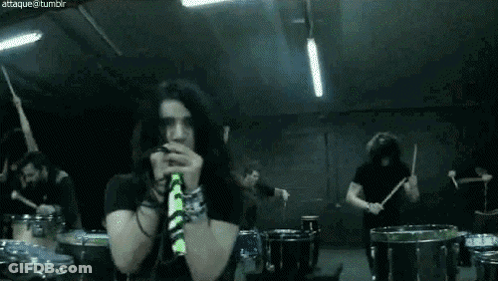 Group Playing Drums In Dark Room With Man On Mic GIF