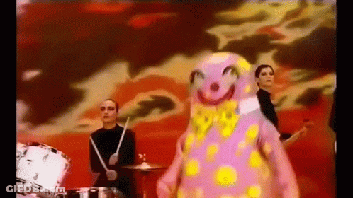Group Playing Drums In Front Of Pink Clown GIF