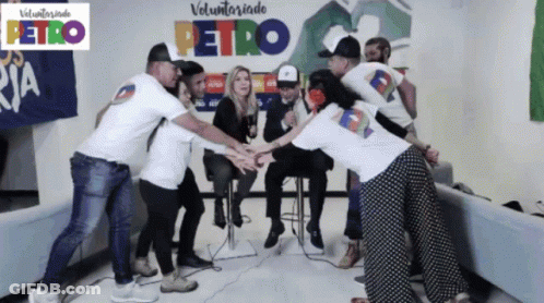 Group Putting Hands Together In Front Of Petro Sign GIF