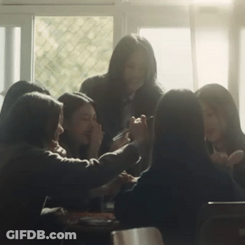 Group Sitting Around Table With Hands On Faces GIF