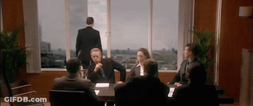Group Sitting Around Table With Man Standing In Window GIF