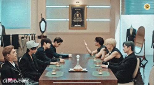 Group Sitting Around Table With Sign Saying 12 GIF