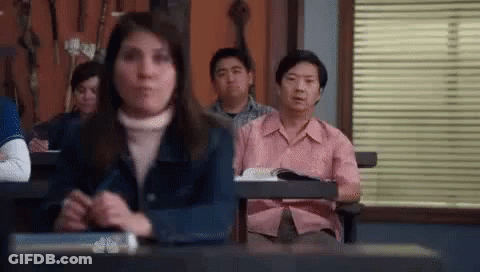 Group Sitting At Desks With Man In Pink Shirt GIF