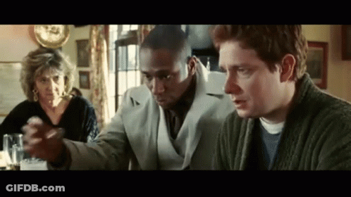 Group Sitting At Table One Holding Something GIF