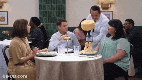 Group Sitting At Table While Man Holds Cake GIF