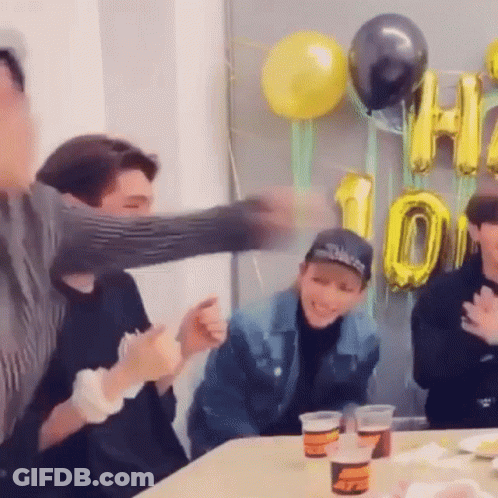 Group Sitting At Table With Balloons And Cups GIF