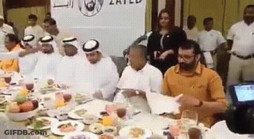 Group Sitting At Table With Food And United Sign GIF