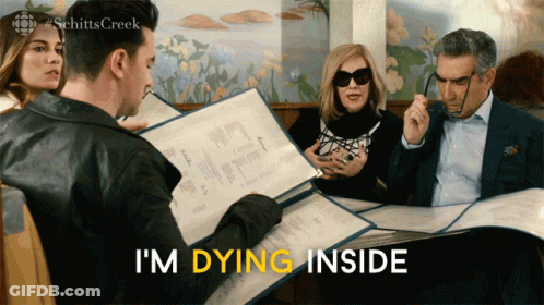 Group Sitting At Table With I'm Dying Inside Sign GIF