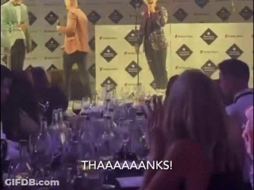 Group Sitting At Table With Thaaaaanks Sign GIF