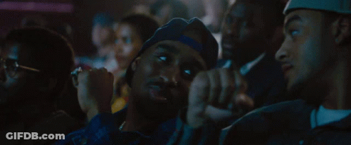 Group Sitting In Dark Room With Hat Saying La GIF