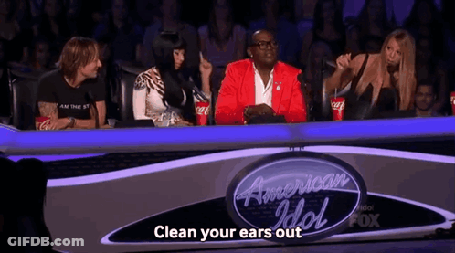 Group Sitting In Front Of Sign Clean Your Ears Out GIF